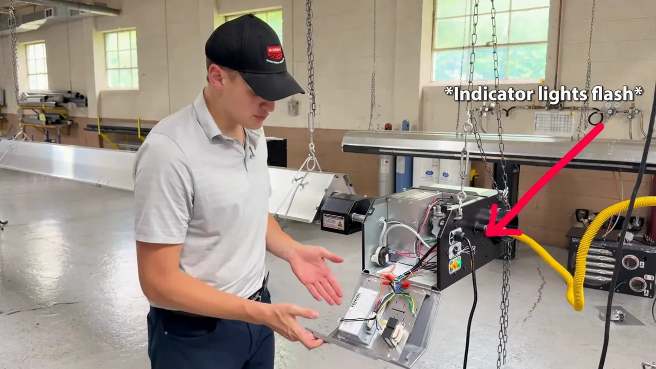 Technician opening radiant heater panel with an arrow pointing to flashing indicator lights