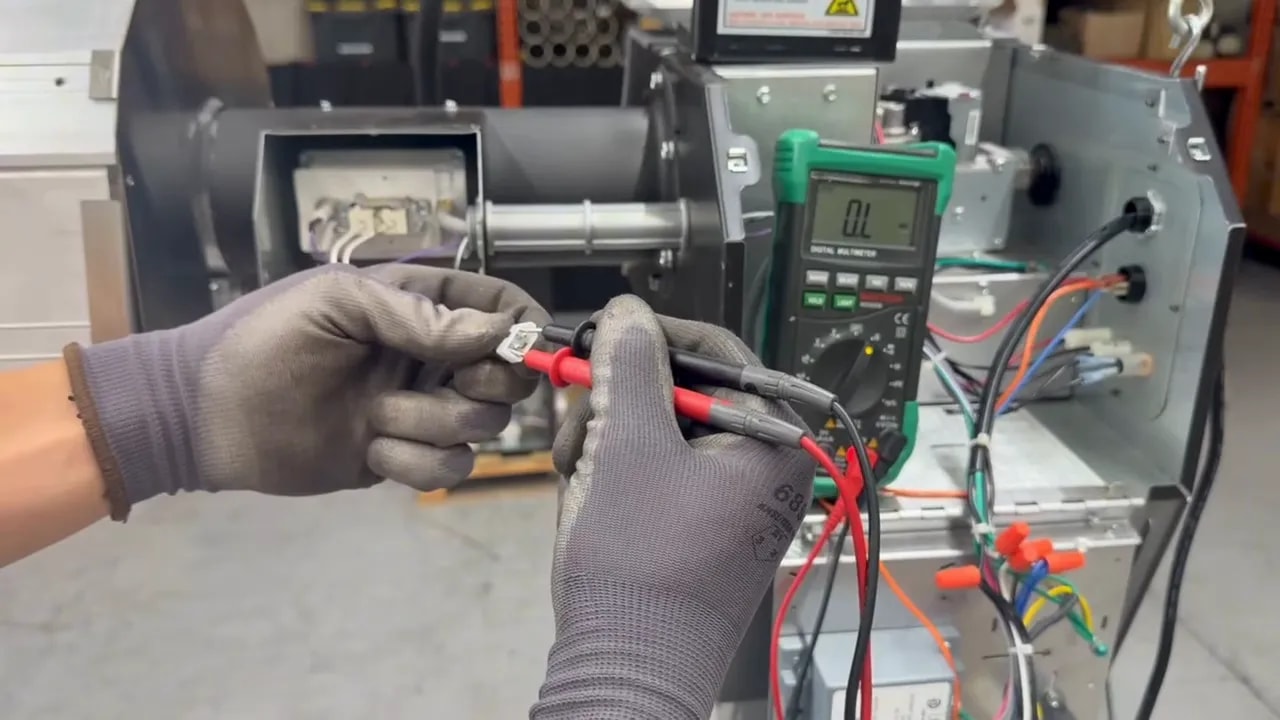 Gloved hands touching multimeter probes to the glow bar connector